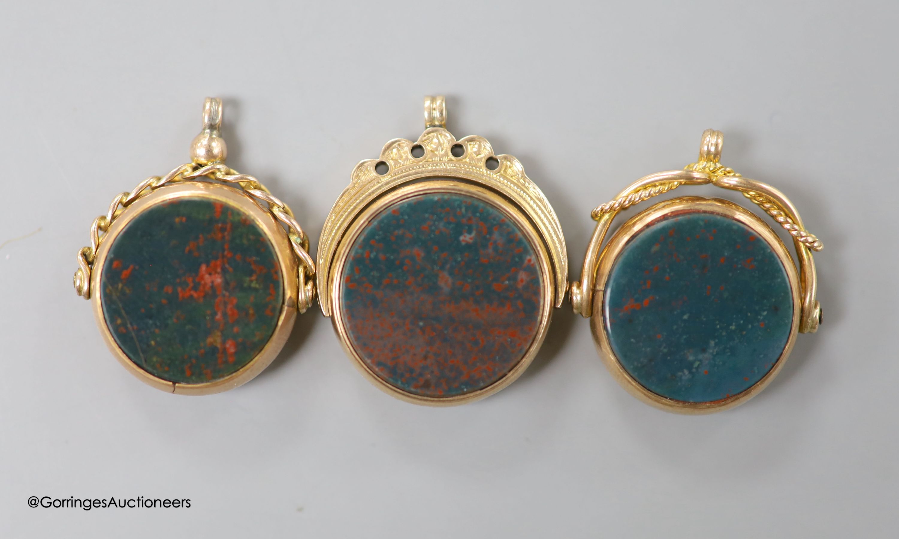 Three assorted late 19th/early 20th century 9ct mounted bloodstone and carnelian set swivelling fob seals, largest overall 29mm, gross weight, 19.7 grams.
